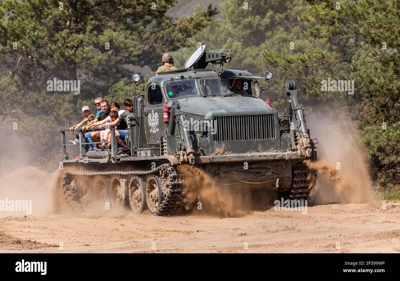 Borne Sulinowo, Polonia – 13 agosto 2023: Veicolo militare cingolato con passeggeri che solleva polvere mentre guida su una strada sterrata Foto Stock