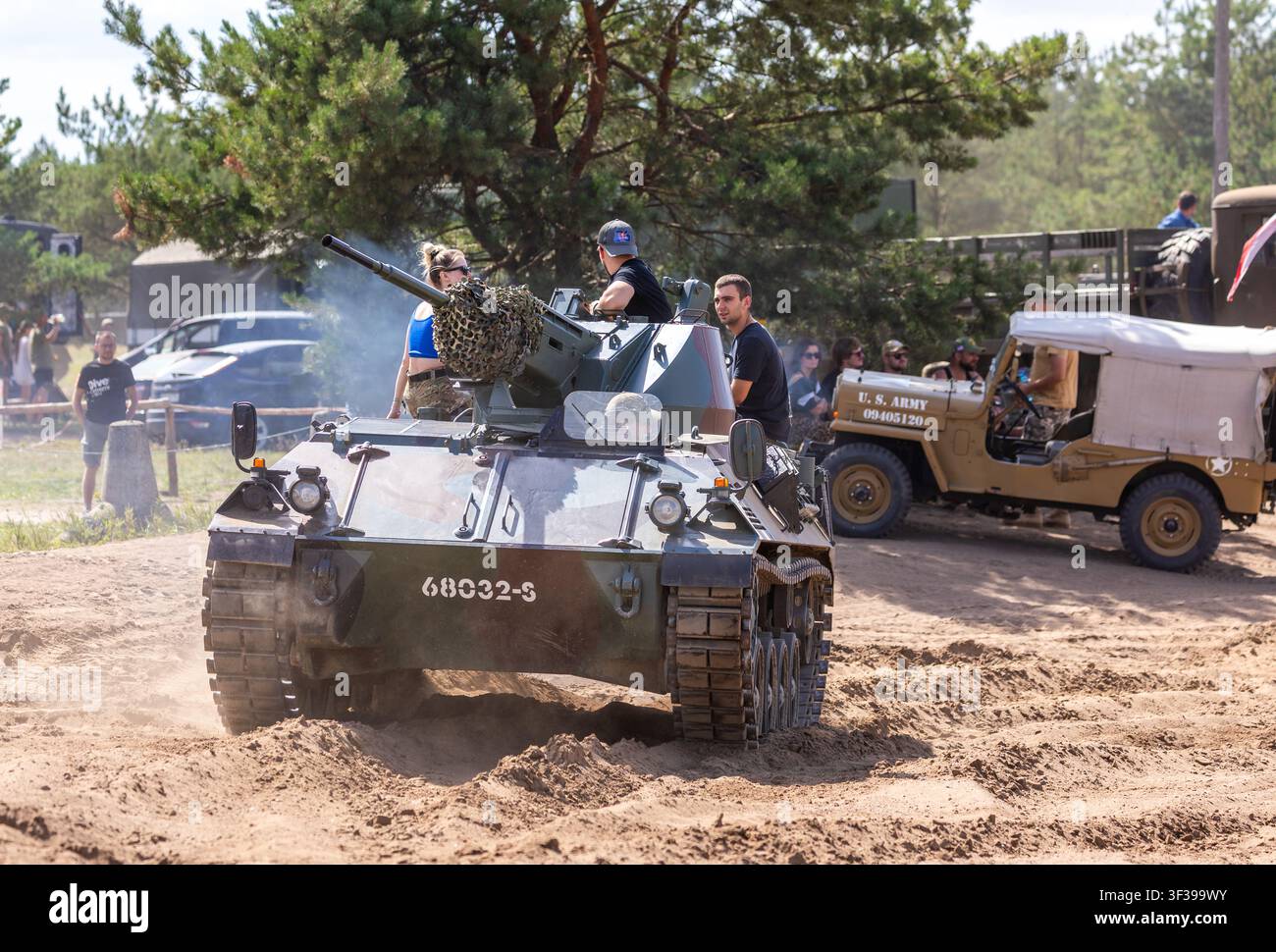 Borne Sulinowo, Polonia – 13 agosto 2023: Veicolo militare blindato in movimento su un sentiero sabbioso con persone a bordo e che osservano Foto Stock