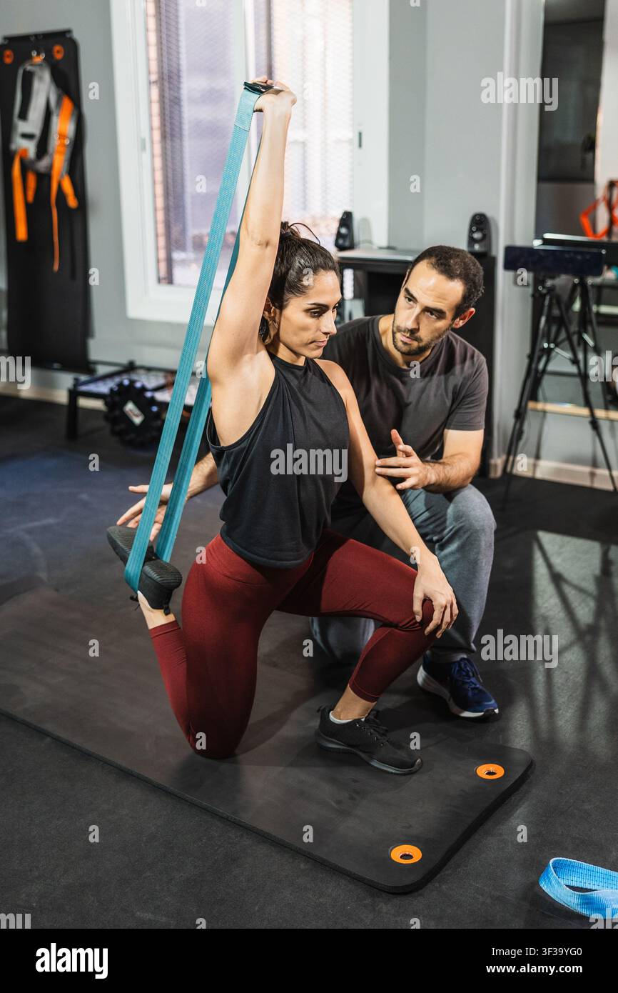 Donna che fa allenamento funzionale con fascia di resistenza e allenatore Foto Stock