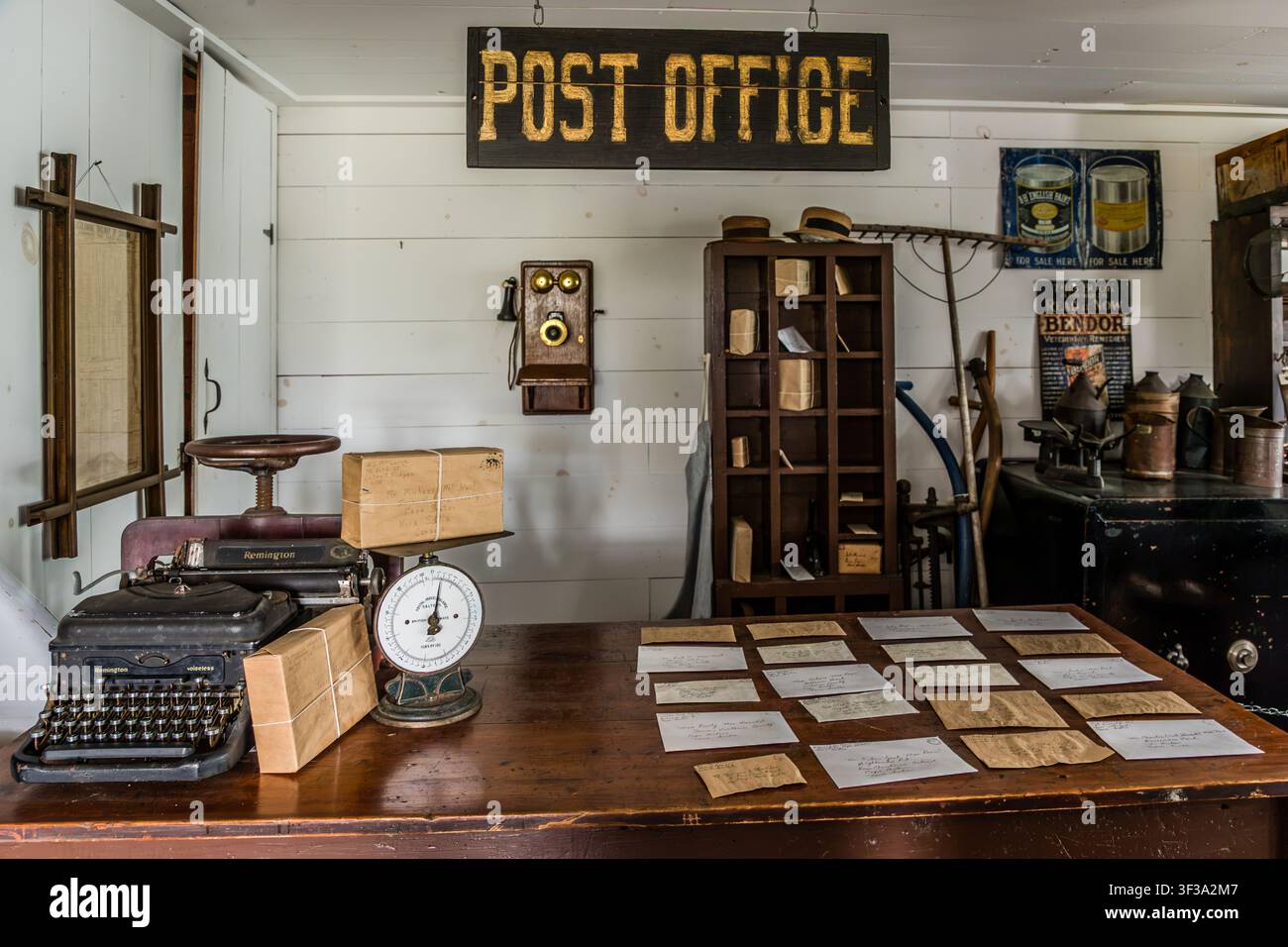 Il bancone della posta dell'A.M. McLeod General Store presso l'Highland Village Museum | Baile nan Gàidheal a Iona, Nuova Scozia, Canada, è stato ricreato con lettere storiche, una macchina da scrivere Remington e una bilancia postale. Un telefono montato a muro è appeso accanto a un armadietto per le cassette postali Foto Stock