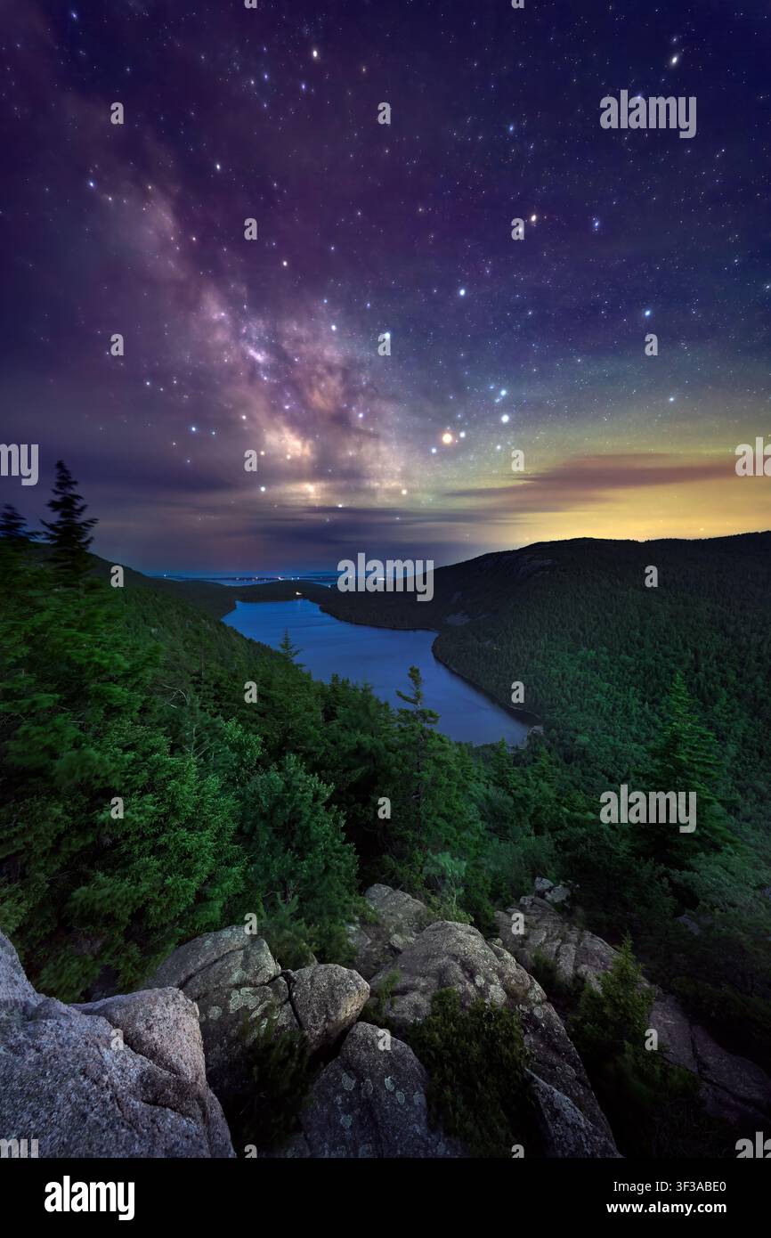 Appollaiato sulla cima del North Bubble nell'Acadia National Park, questo affascinante paesaggio notturno cattura la serenità del Jordan Pond sotto un cielo stellato. Foto Stock