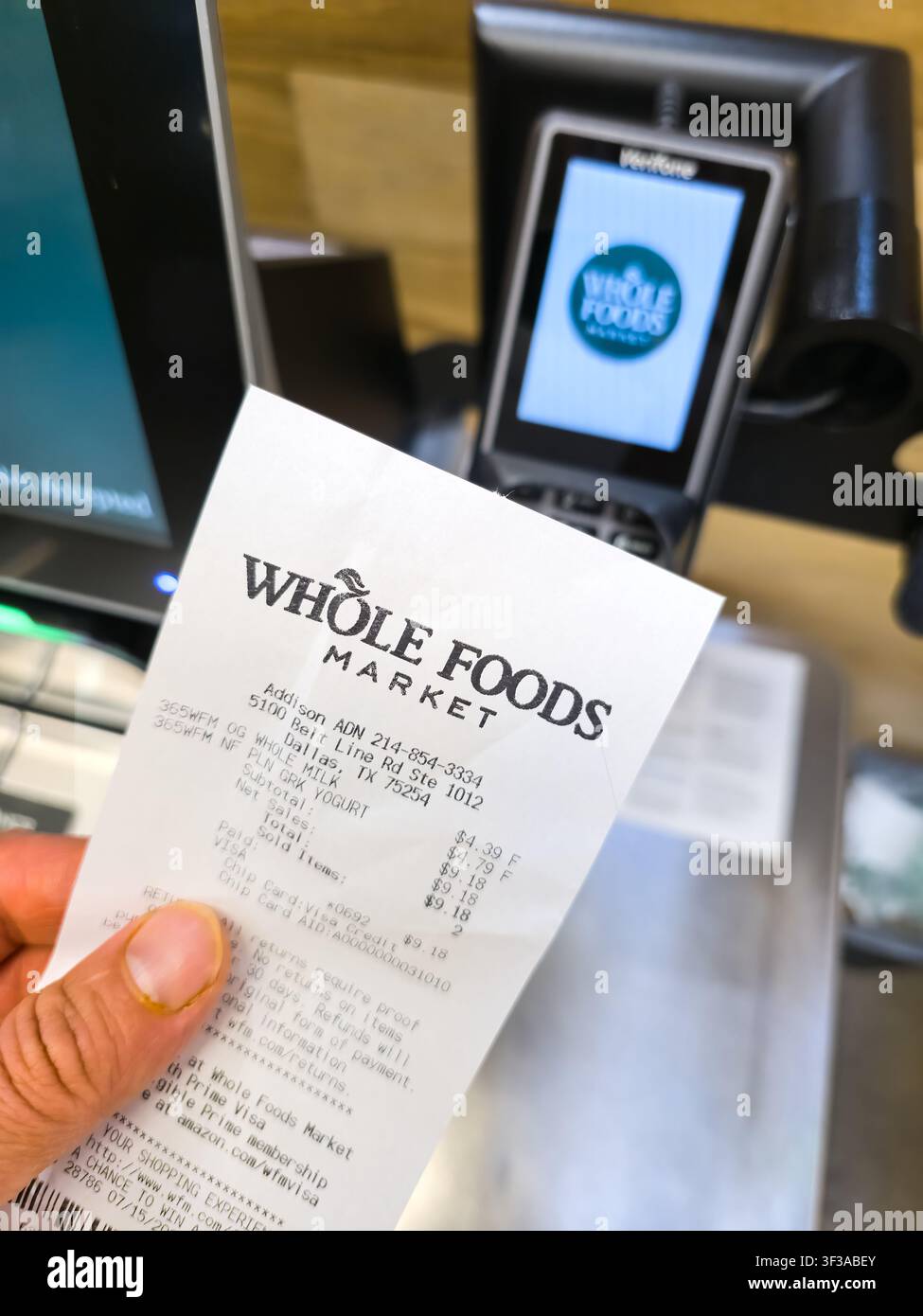 DALLAS - 15 LUGLIO 2026: Un cliente tiene una ricevuta di Whole Foods Market vicino a un terminale di pagamento all'interno della filiale di Dallas. Whole Foods Market, noto per Foto Stock