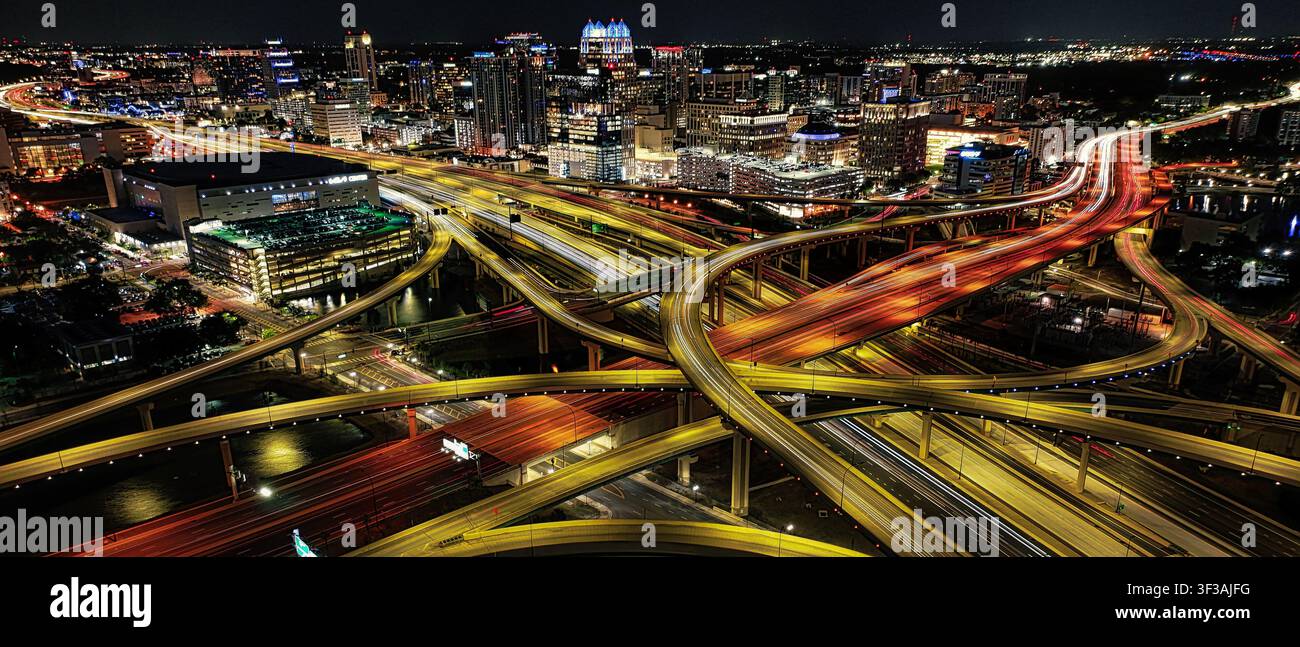Le tracce luminose a strati dei droni tracciano la I-4 e la 408 attraverso il centro di Orlando, brillando oltre il Kia Center in uno spettacolo notturno della città mozzafiato. Foto Stock