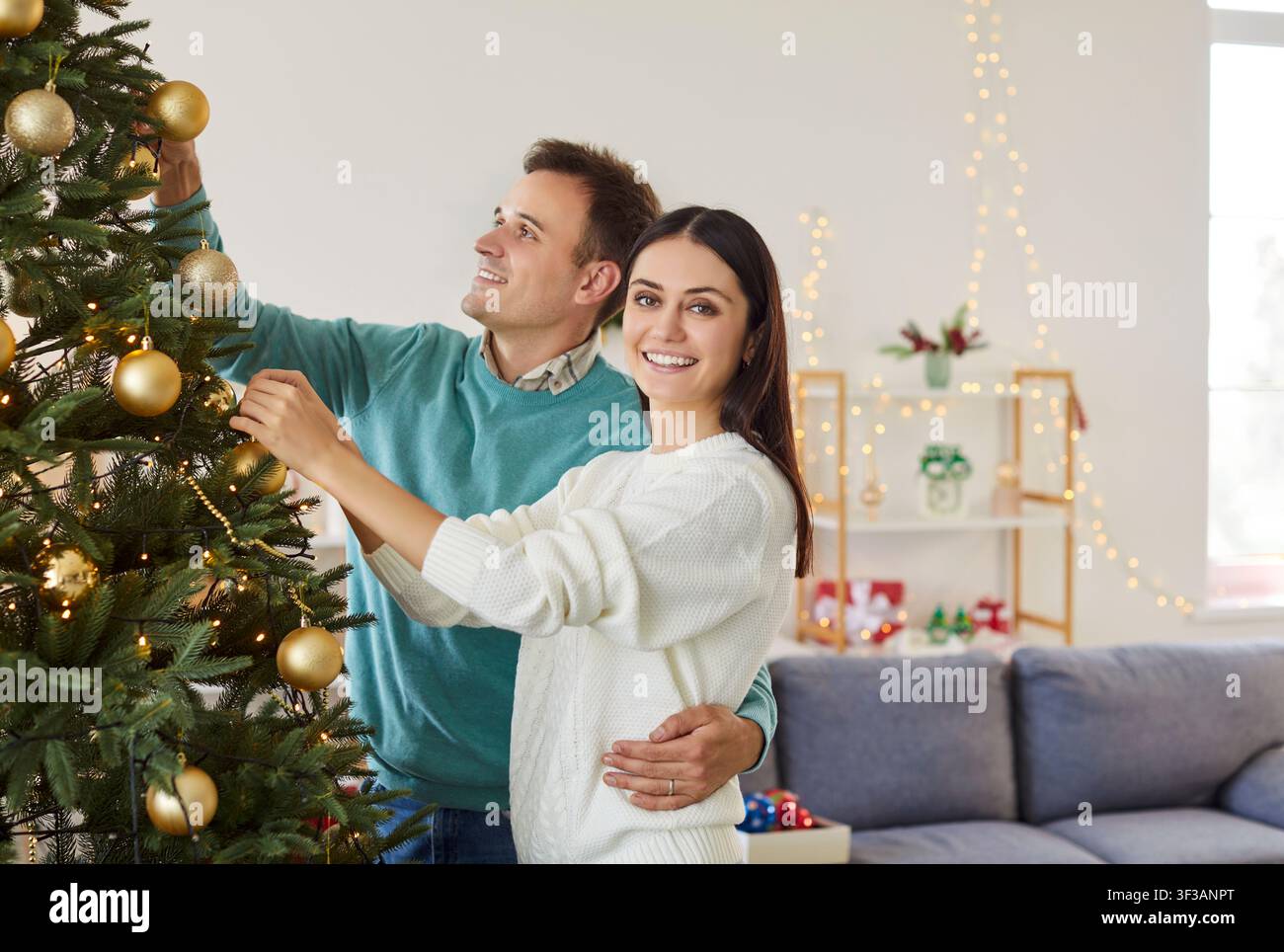 Ritratto di una coppia felice che decora un albero durante il Capodanno o il Natale a casa Foto Stock