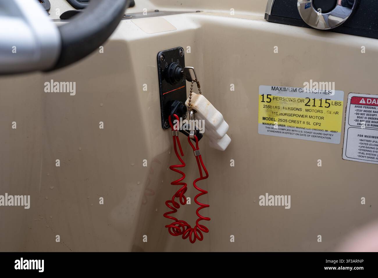 Una vista ravvicinata del pannello dell'accensione di una barca che mostra un cordino di sicurezza rosso (interruttore di spegnimento del motore) appeso alla chiave sulla console. Foto Stock