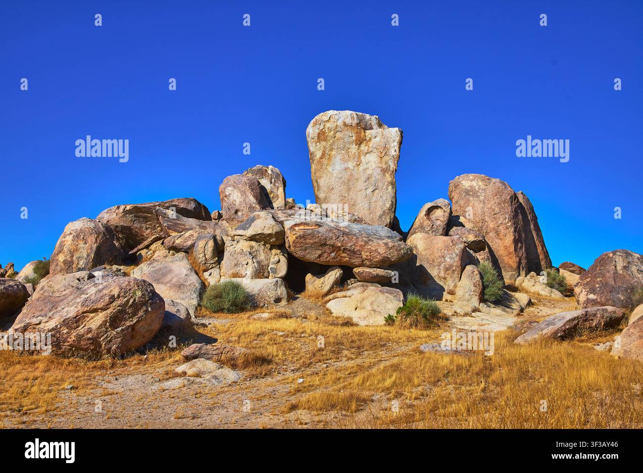 Formazioni rocciose e erbe secche sotto un cielo blu terso a Trona, California Foto Stock