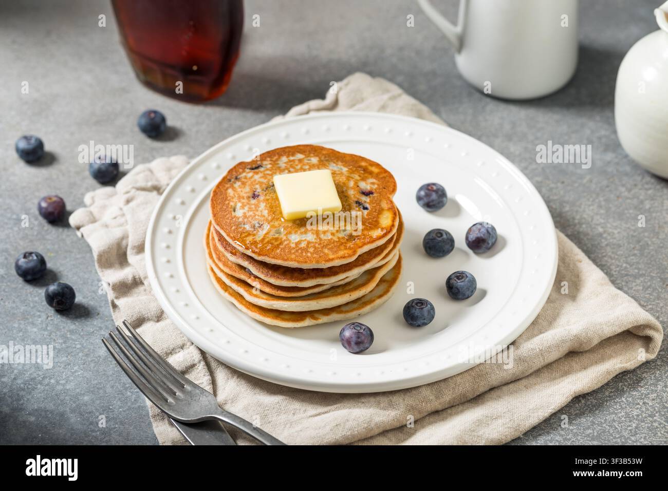 Dolce impilata di pancake fatti in casa con mirtilli, burro e sciroppo d'acero Foto Stock