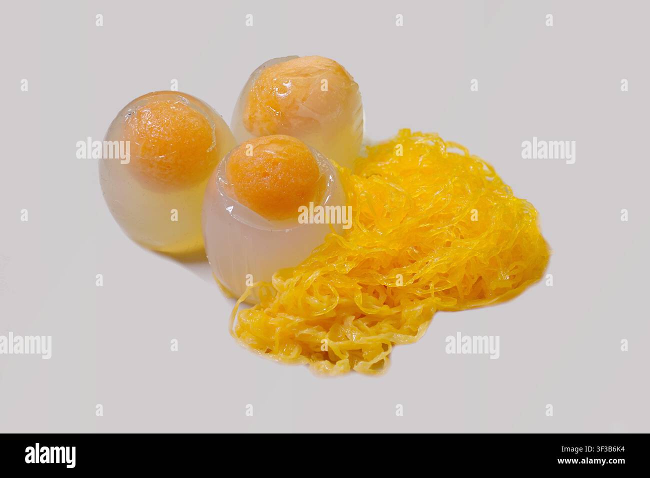 Prima di gelatina di uovo di anatra, un dessert thailandese unico a base di agar modellato in gusci d'uovo, servito con fili dorati zuccherati di foi thong Foto Stock