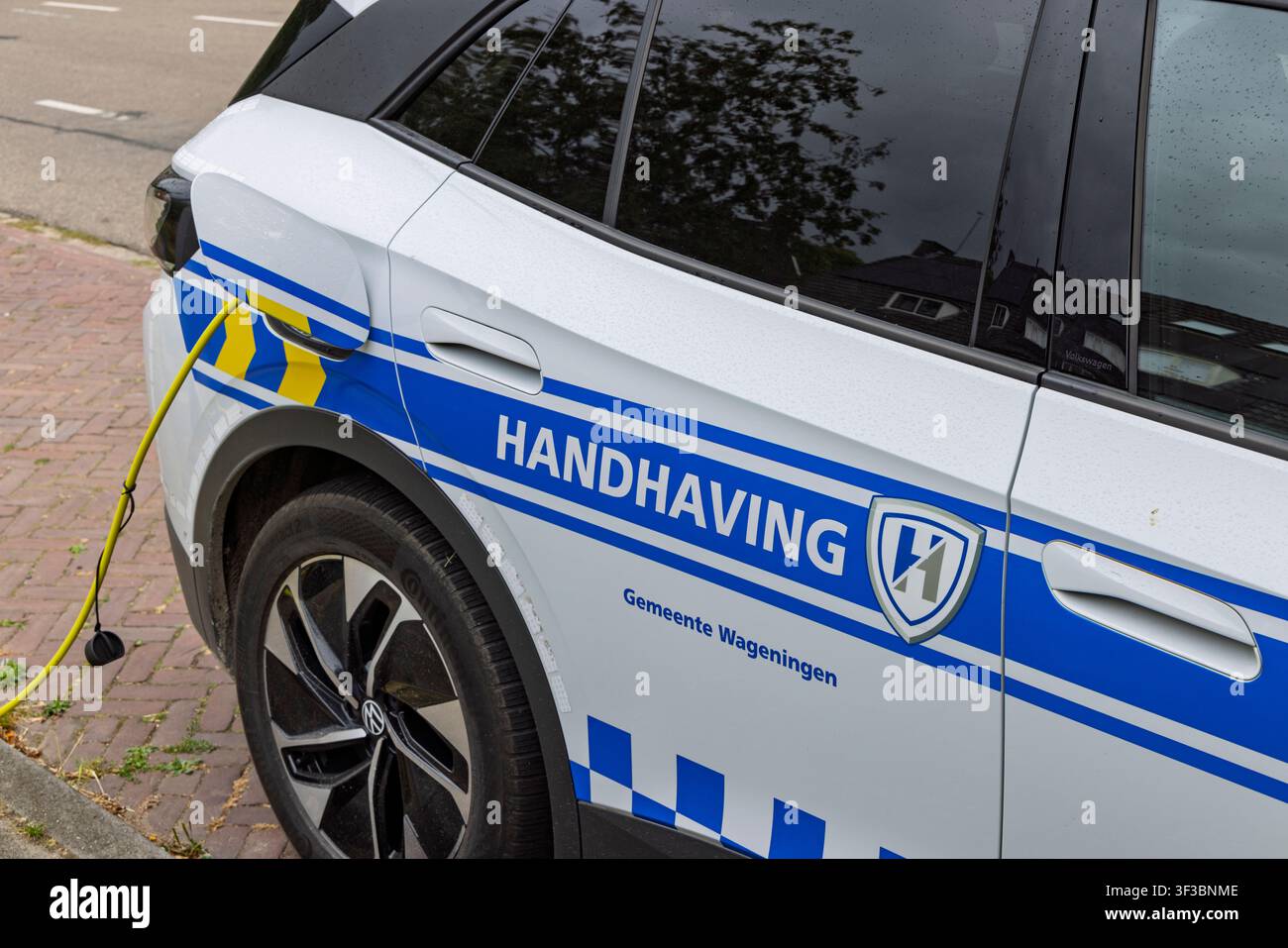 Wageningen, Paesi Bassi - 22 luglio 2026: Primo piano di un veicolo elettrico di applicazione comunale Handhaving Gemeente Wageningen collegato per la ricarica o Foto Stock