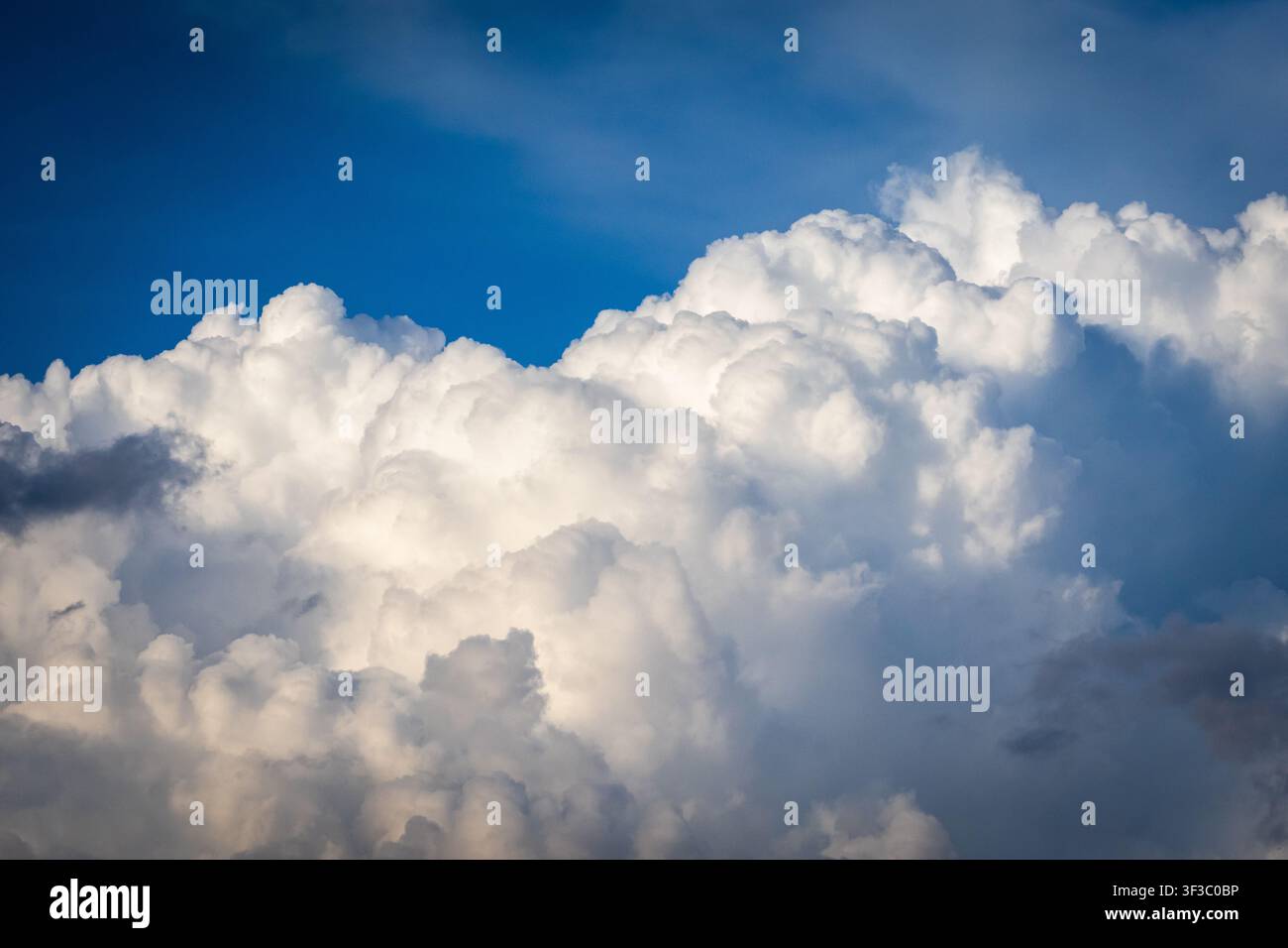 Una luce soffusa sfiora un volto scolpito di nuvole, creando blu sottili e grigi caldi che suggeriscono profondità ed emozione nel cielo, un dolce ritratto della pace Foto Stock