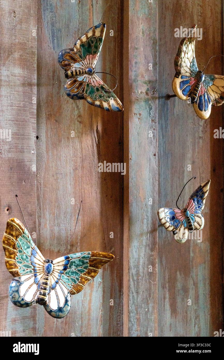 Una decorazione a farfalla in legno su un muro rustico al ristorante NdalemRatu a Malang, Giava Orientale, Indonesia, in un pomeriggio. Foto Stock