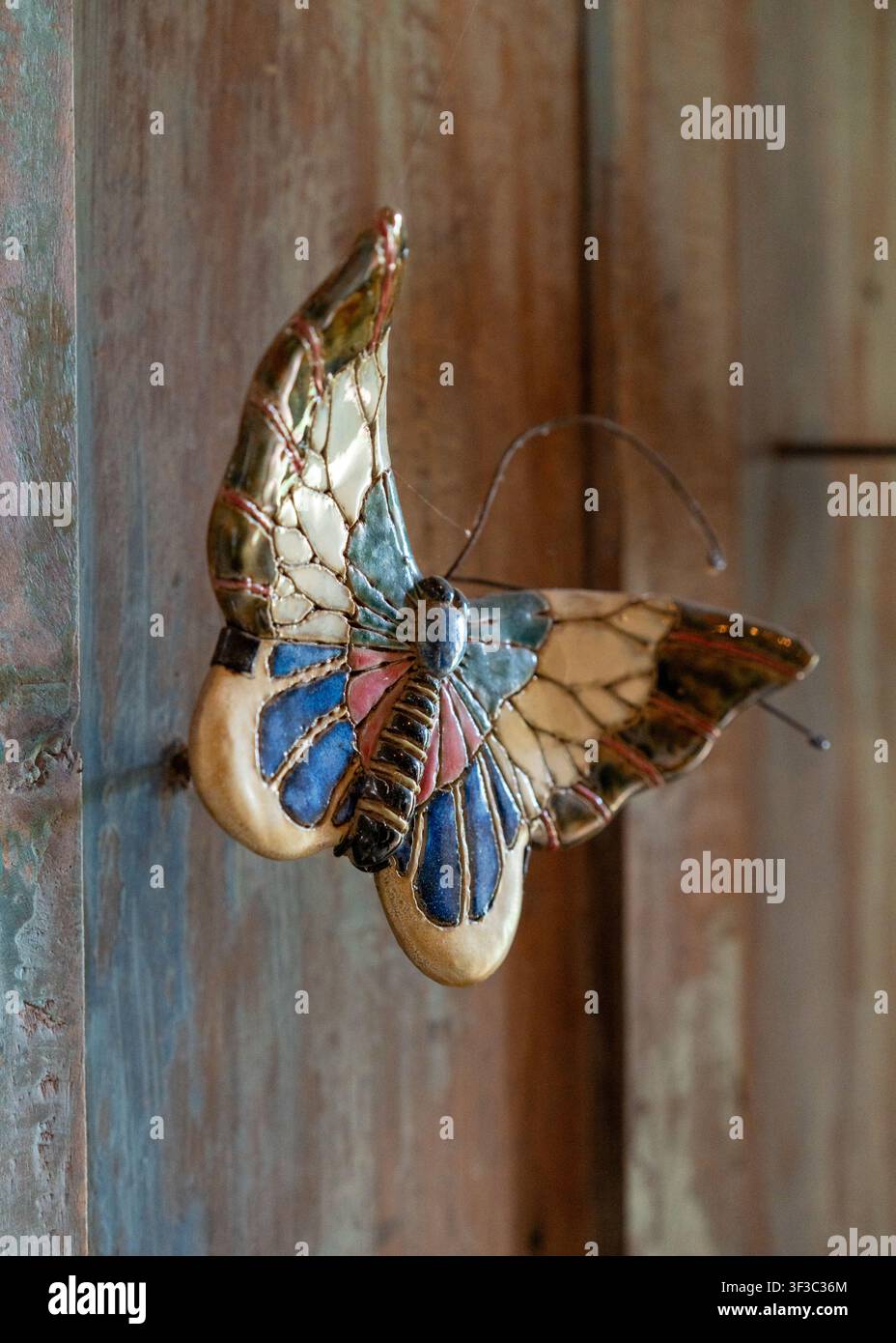 Una decorazione a farfalla in legno su un muro rustico al ristorante NdalemRatu a Malang, Giava Orientale, Indonesia, in un pomeriggio. Foto Stock