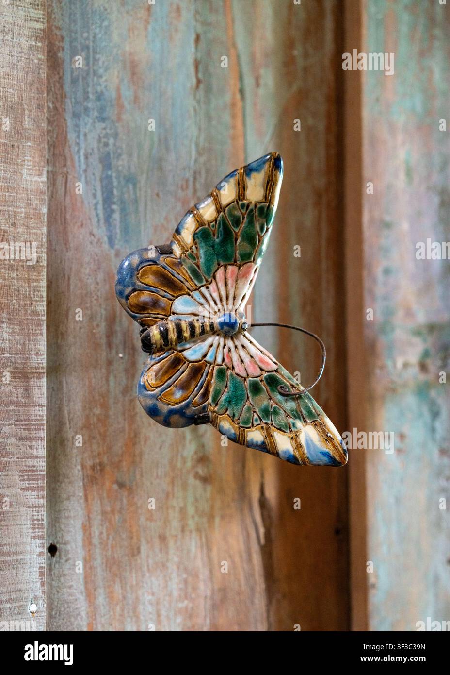 Una decorazione a farfalla in legno su un muro rustico al ristorante NdalemRatu a Malang, Giava Orientale, Indonesia, in un pomeriggio. Foto Stock