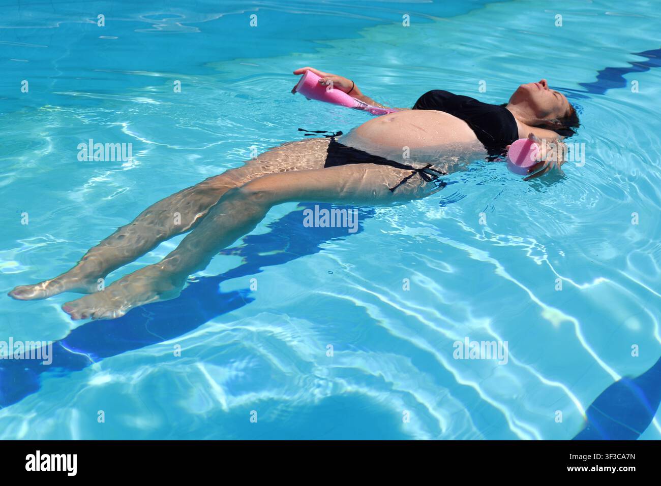 Donna incinta che fa esercizio in acqua per il benessere e il rilassamento prenatale Foto Stock