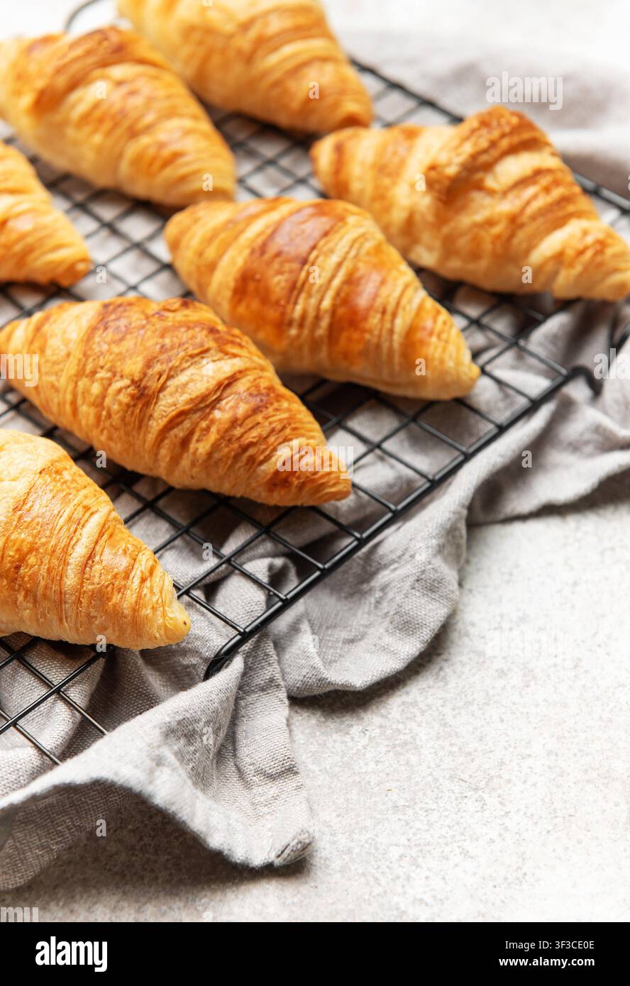 Croissant dorati appoggiati su una griglia metallica, creando un'allettante scena per la colazione Foto Stock