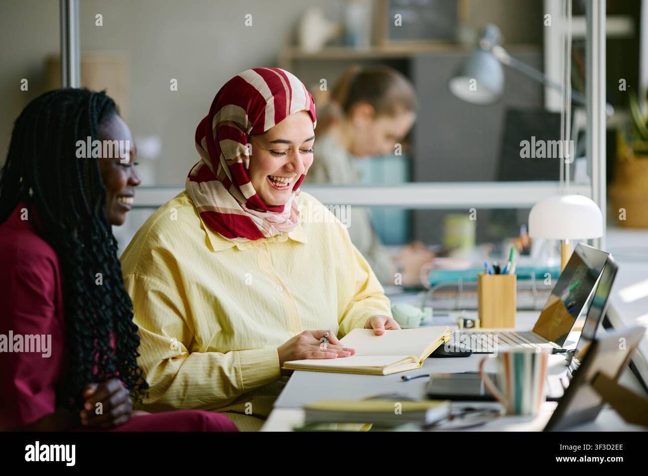 Donna nera e donna musulmana collaborano in un ufficio moderno Foto Stock
