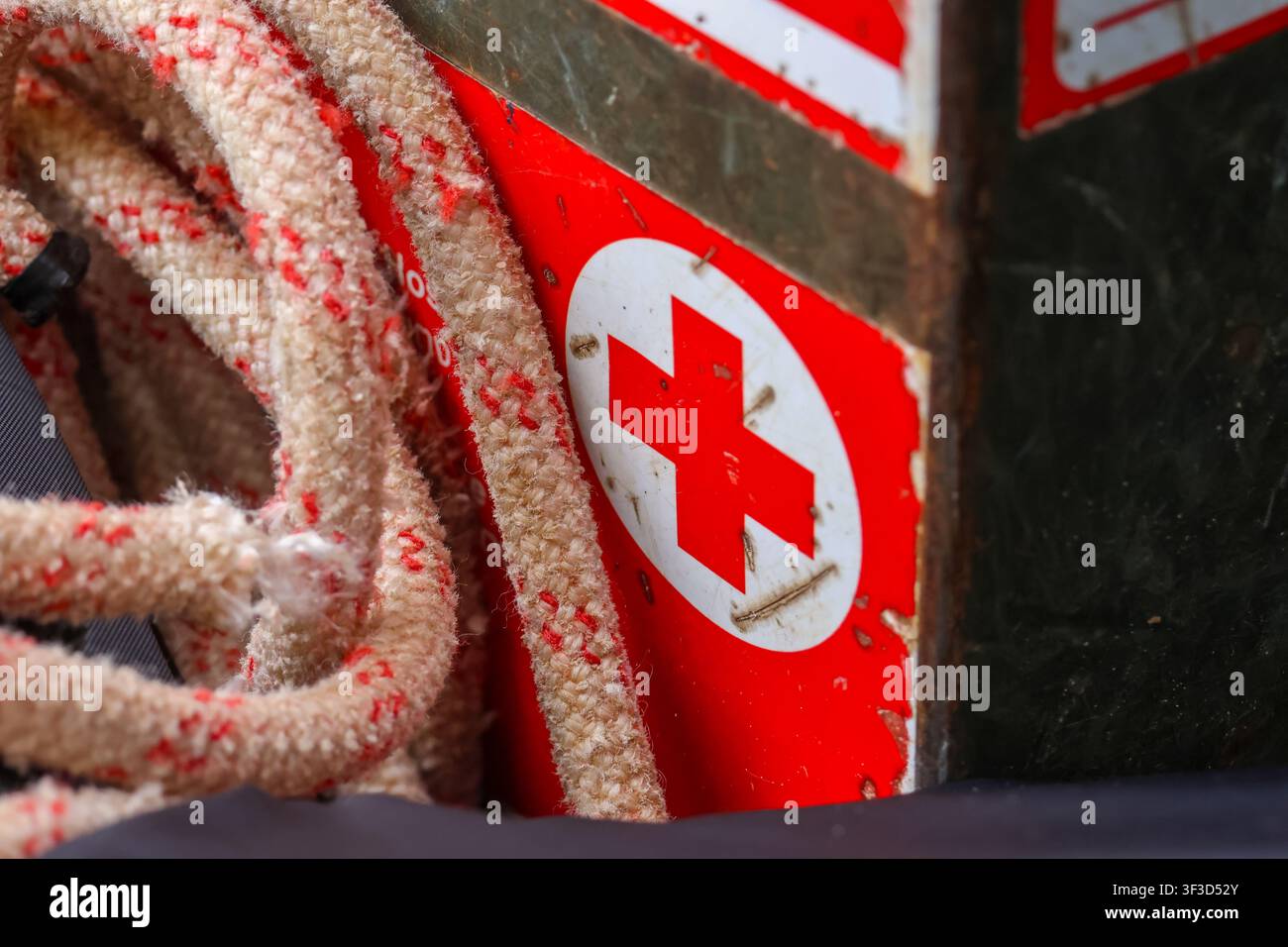 Una scatola di pronto soccorso consumata con corda arrotolata, simbolo di emergenza e superfici ruvide che trasmettono prontezza e uso robusto Foto Stock