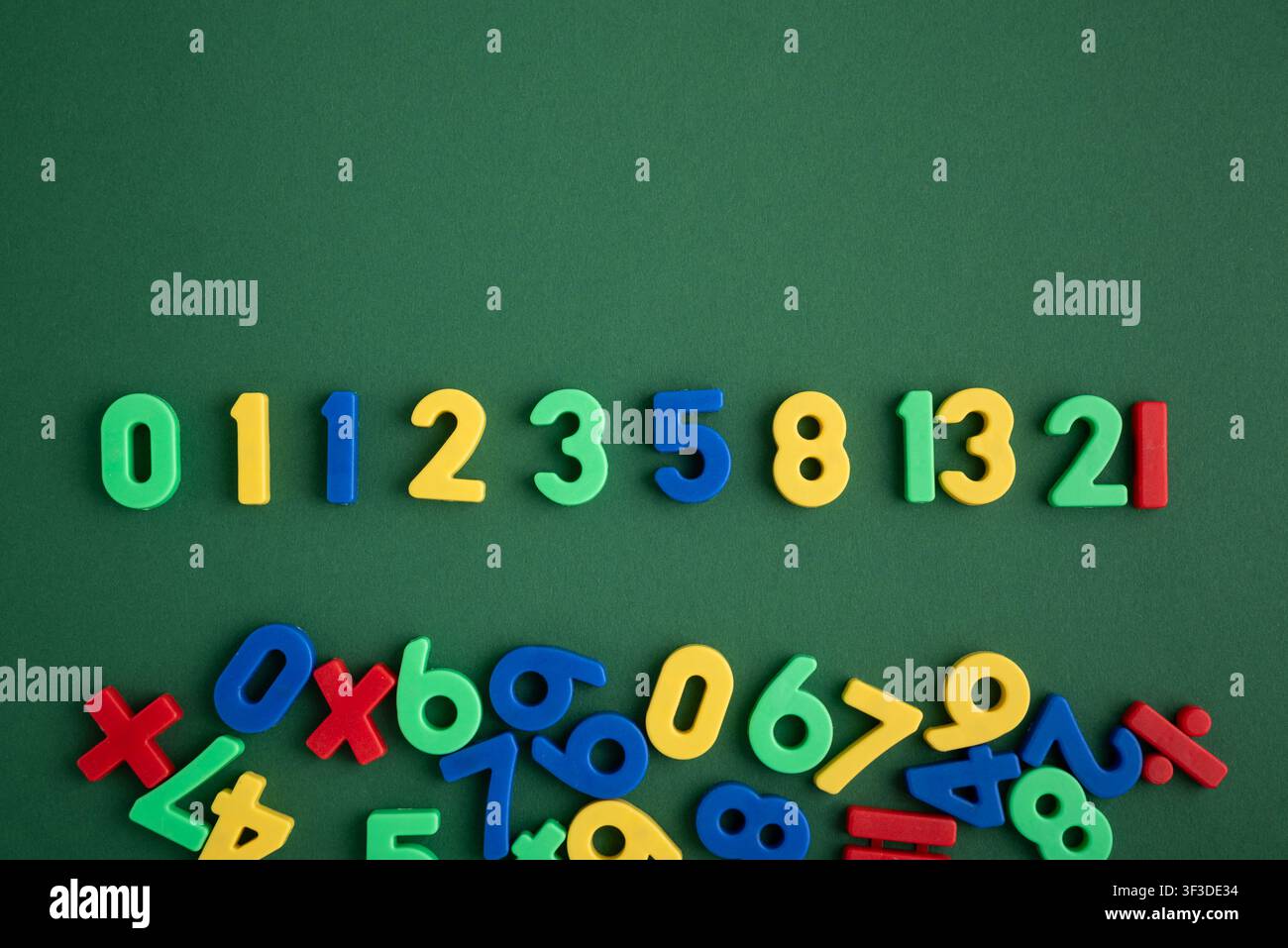 Numeri di plastica colorati formano la sequenza di Fibonacci disposti su uno sfondo verde scuro con una pila aggiuntiva di numeri sparsi e matematica Foto Stock