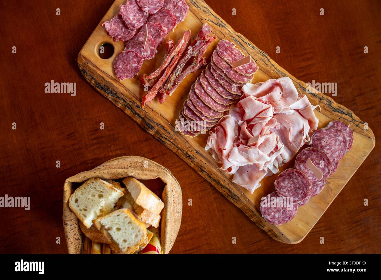Tavola di salumi con salumi tipici italiani - salame, pittina della zona di Pordenone, carne affumicata essiccata - su legno rustico. Prodotti internazionali simili Foto Stock