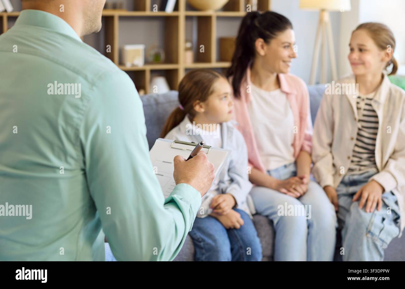 Terapeuta familiare con clipboard che consiglia madre e figlie in una seduta a casa Foto Stock