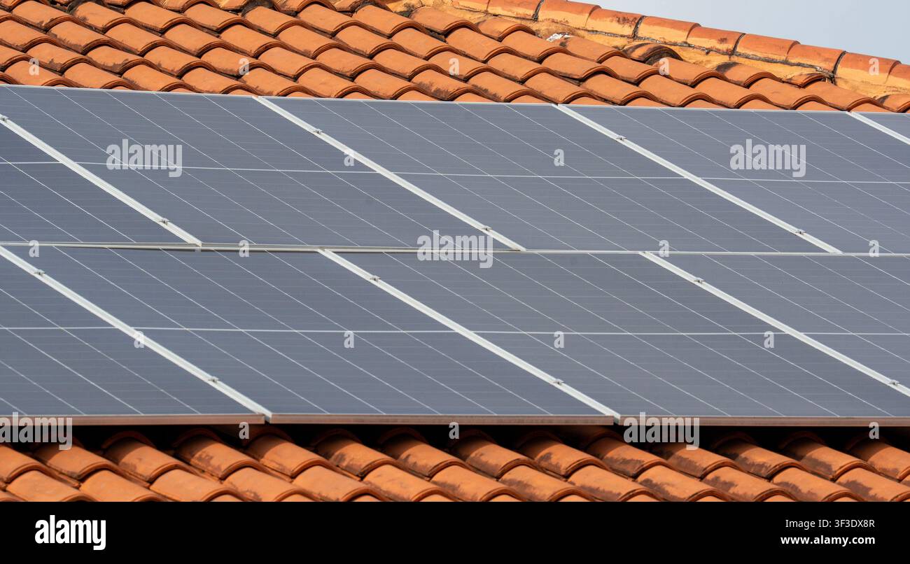 Array di pannelli solari montati su un tetto con tegole in terracotta, vista angolare Foto Stock