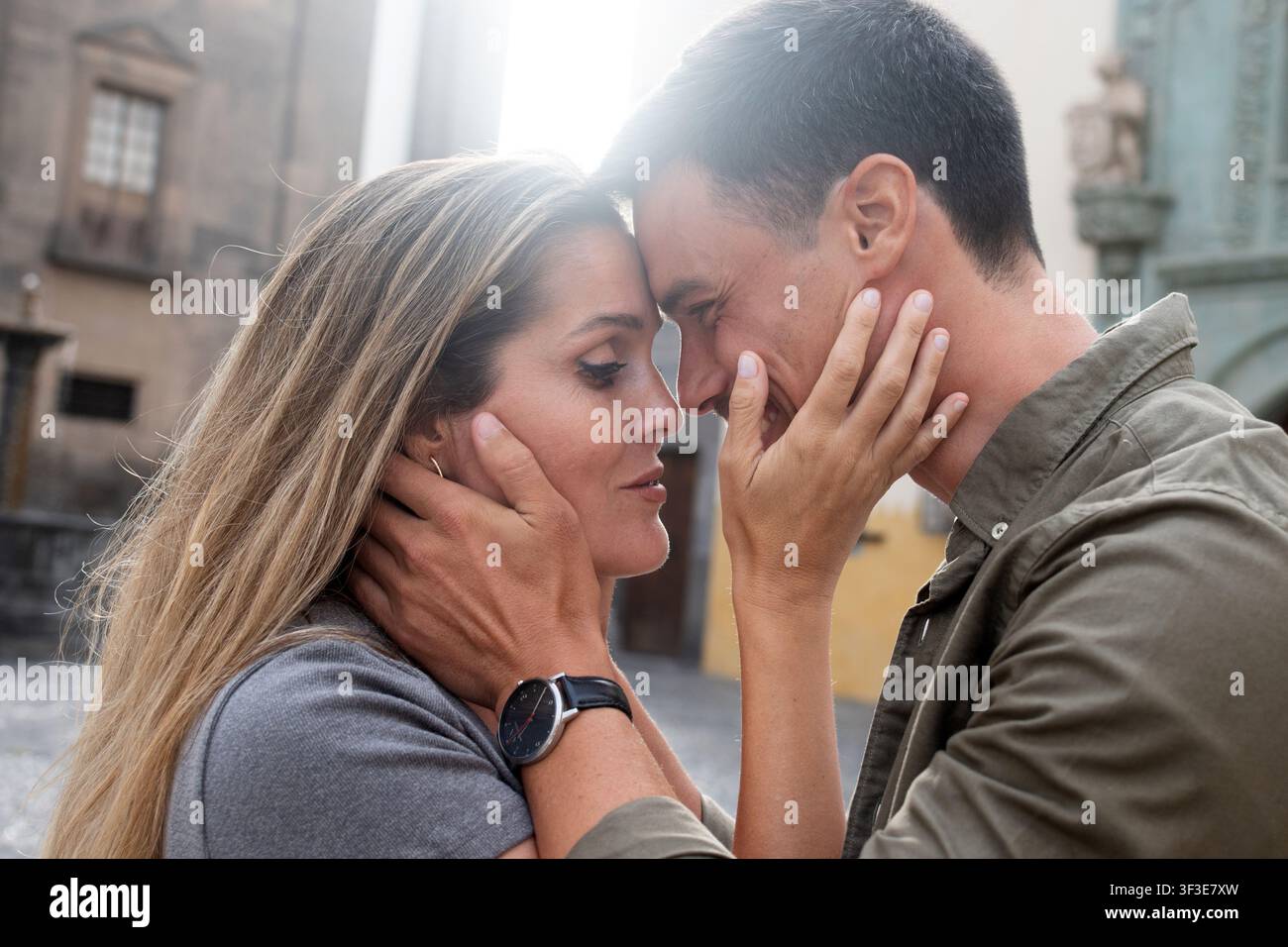 Coppia innamorata che si abbraccia con le fronti che si toccano mentre condividono un momento intimo in una piazza storica della città. Foto Stock
