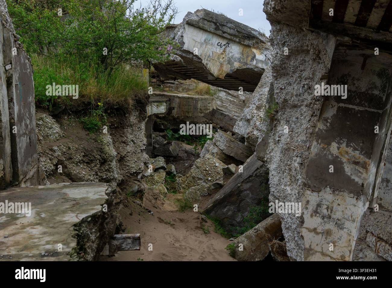 Interno crollato delle storiche Fortezze Nord a Liepaja, Lettonia, che mostra strutture in cemento rotte, macerie e vegetazione. Foto Stock