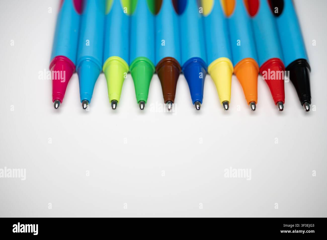 Penne e pennarelli colorati disposti come cancelleria creativa, rappresentando educazione, scrittura, disegno, organizzazione ed espressione artistica Foto Stock