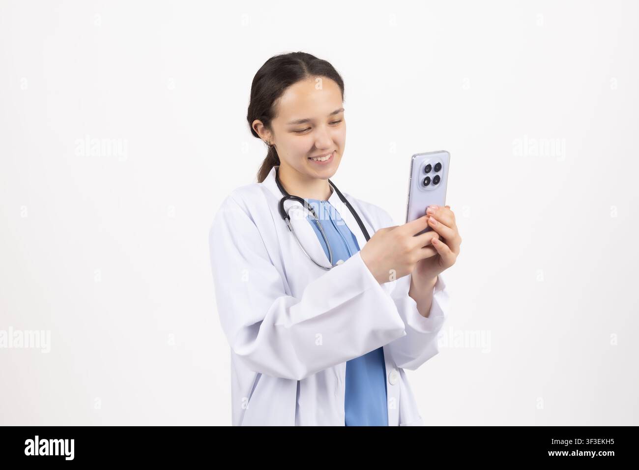 Medica in camice da laboratorio che tiene uno smartphone e controlla un'app medica Foto Stock