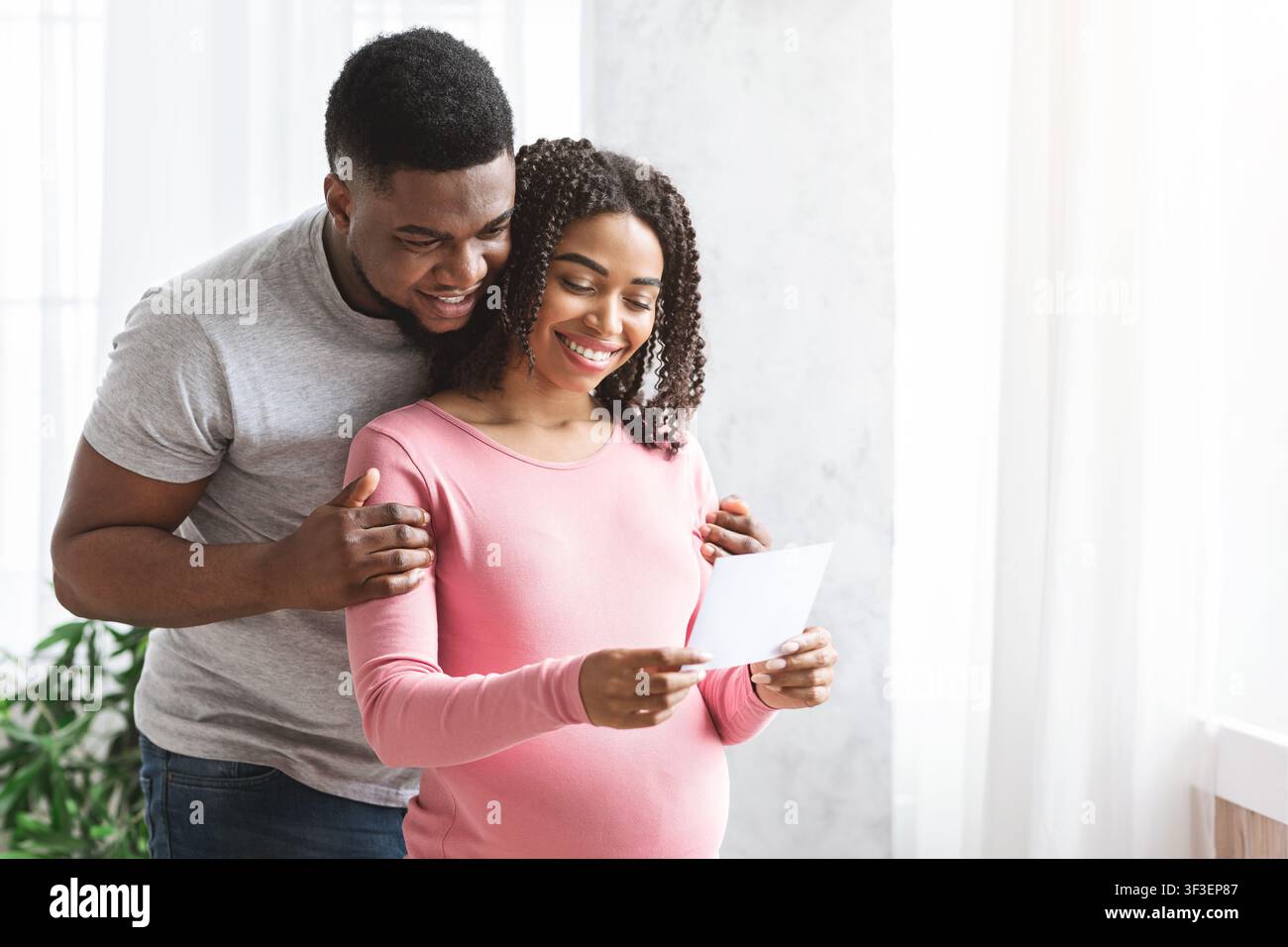 Donna incinta e suo marito che guarda l'immagine Foto Stock