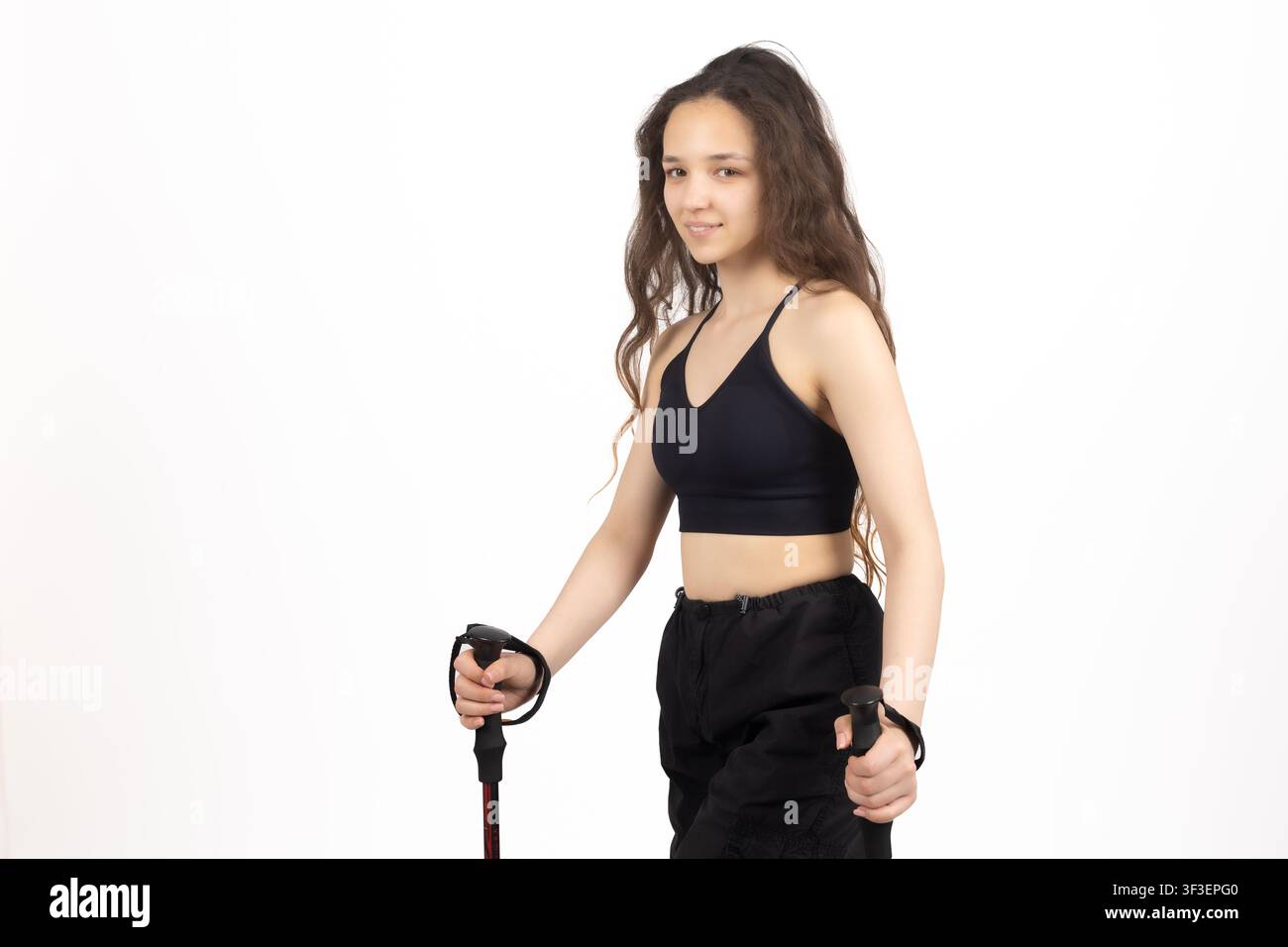 Giovane donna atletica che tiene bastoni da trekking posa in studio isolata Foto Stock