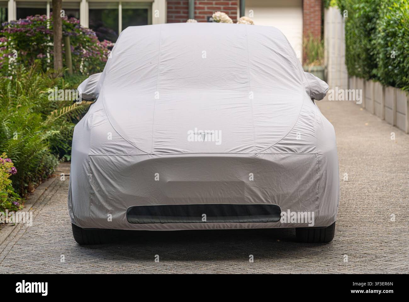 Ede, Paesi Bassi, 23.06.2026, Auto Tesla coperta parcheggiata all'aperto sotto una copertura protettiva resistente alle intemperie su misura Foto Stock