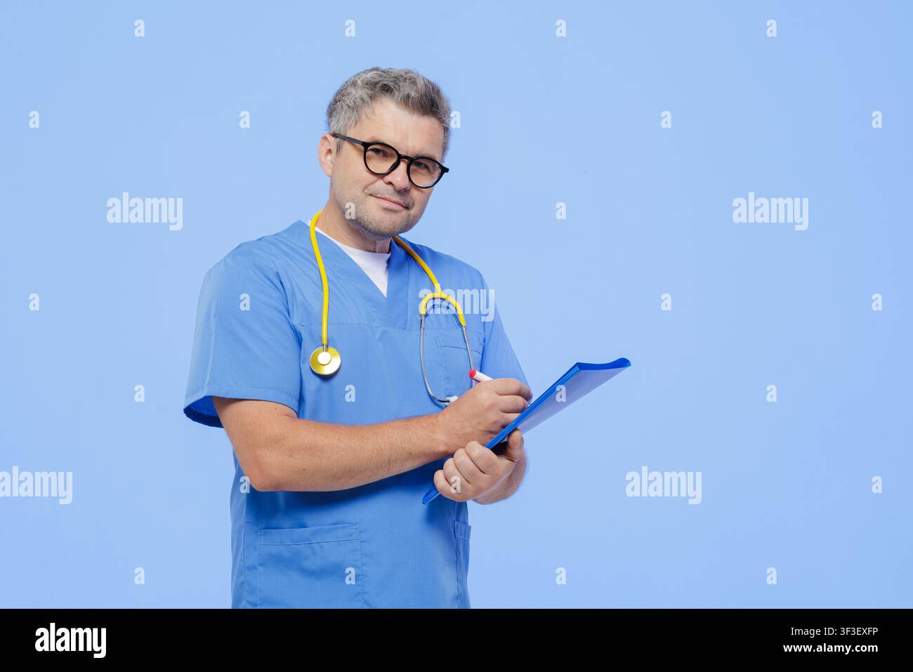 Un medico professionista in camice e stetoscopio, che prende attentamente appunti su una clipboard durante un appuntamento medico. Foto Stock