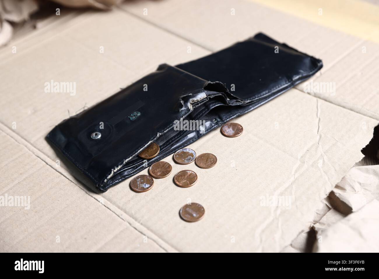 Situazione finanziaria precaria. Vecchia borsa con monete su cartone, primo piano Foto Stock