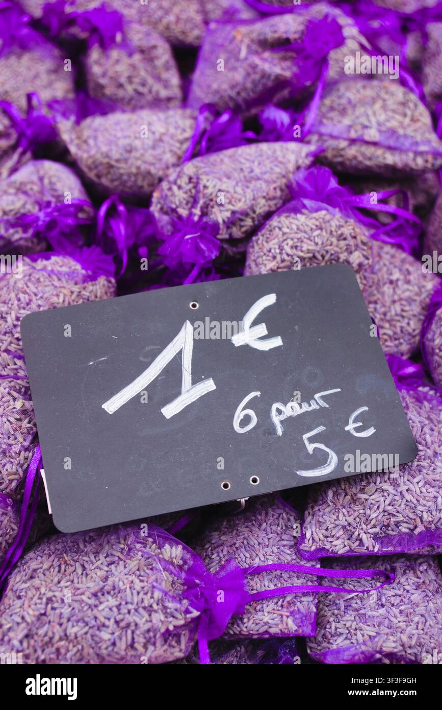 Piccoli sacchetti viola a rete pieni di lavanda essiccata profumata in vendita su un espositore di mercato nella Provenza, Francia, con un cartello del prezzo scritto a mano. Foto Stock