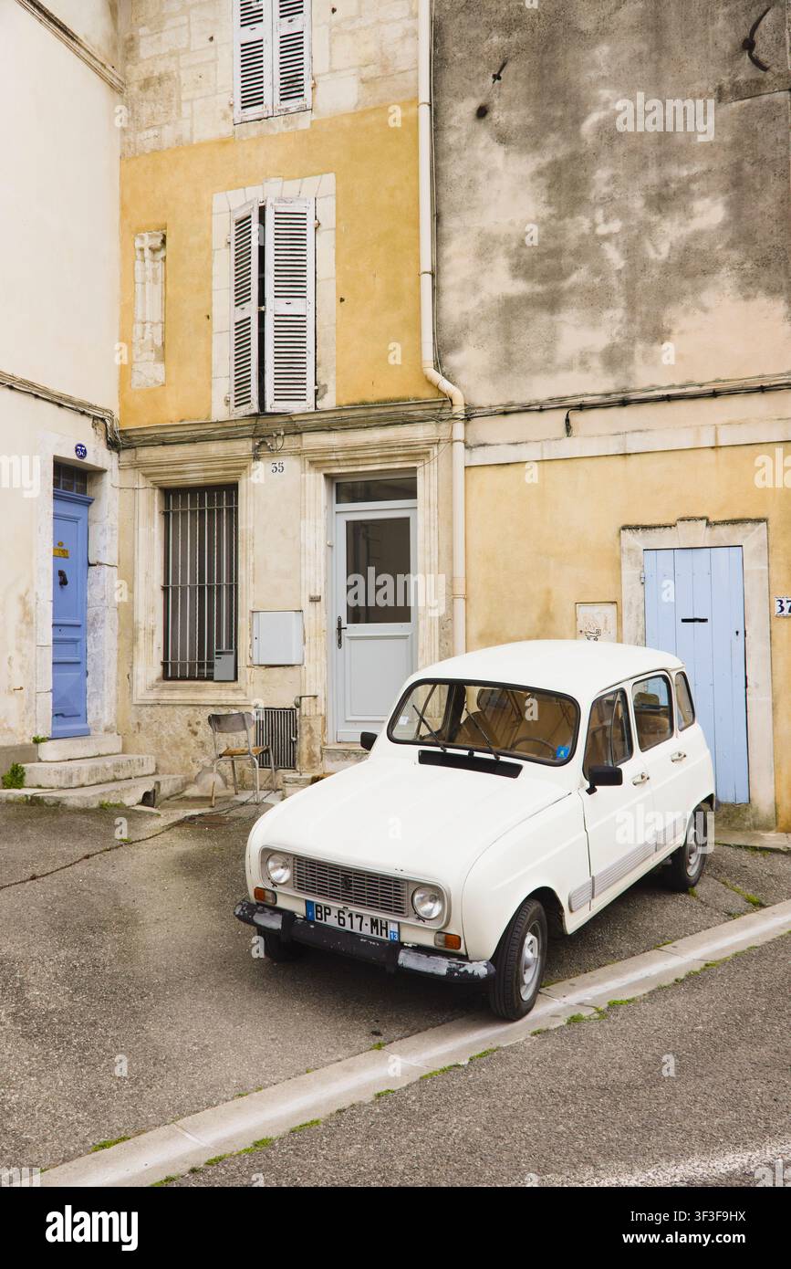 Un'auto classica Renault 4 bianca vintage parcheggiata in una strada tranquilla davanti a case storiche in pietra con persiane blu ad Arles, Francia. Foto Stock