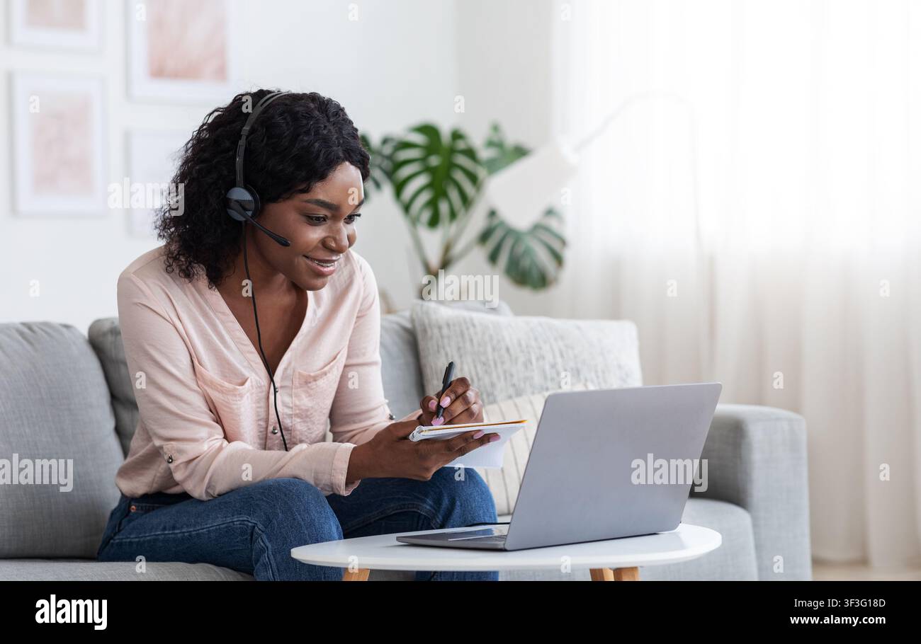 Formazione online. Giovane femmina nera studia online da casa con computer portatile Foto Stock
