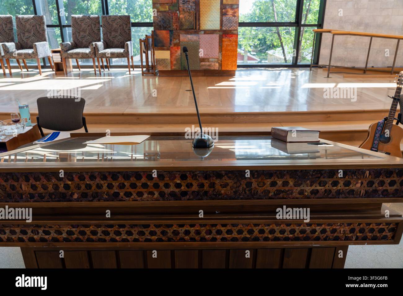 Interno di sinagoga con bimà decorata, microfono, libro religioso, piattaforma in legno e luce naturale, che combina un design spirituale Foto Stock