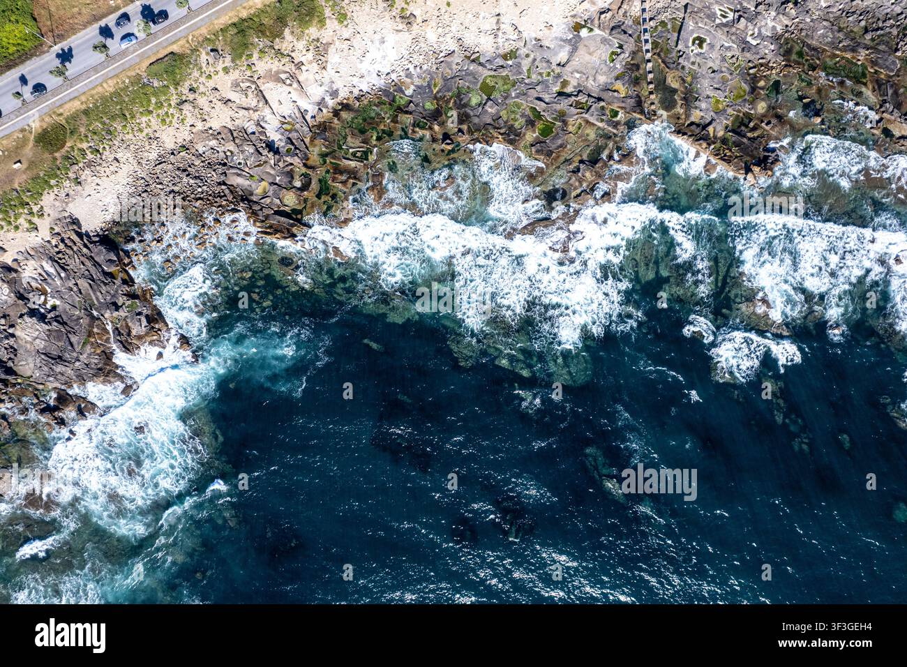Paesaggio mozzafiato che mostra il contrasto tra un'autostrada asfaltata e scogli pericolosi dell'oceano visti dall'alto Foto Stock