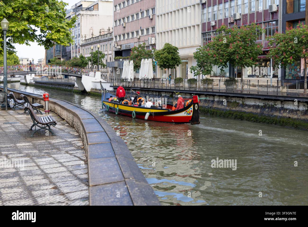 Aveiro, Portogallo - 10 maggio 2026: Barca tradizionale moliceiro che naviga sotto il famoso Ponte dell'Amicizia (Ponte Lacos de Amizade) decorato con nastri Foto Stock