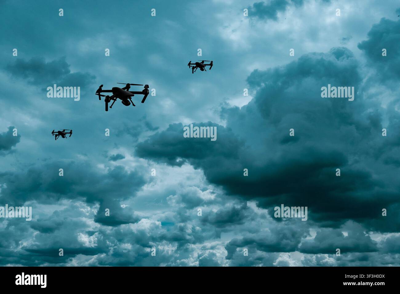 Tre droni aerei senza pilota che volano sotto nuvole tempestose scure, illustrando sorveglianza, tecnologia di sicurezza e sciami di droni Foto Stock