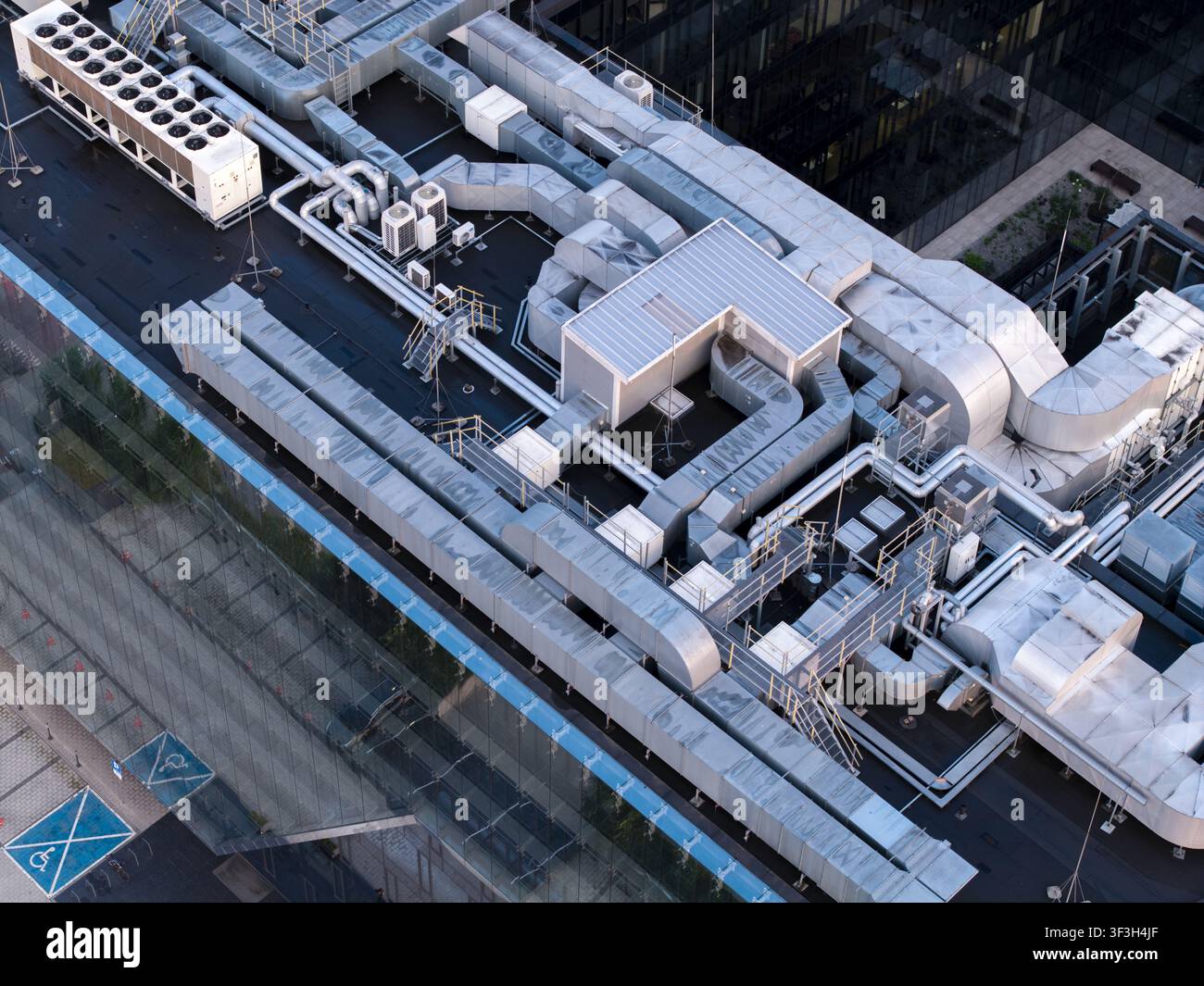 Vista aerea del complesso sistema di raffreddamento HVAC sul tetto di un moderno edificio per uffici, con condotti di ventilazione metallici e infrastrutture industriali Foto Stock