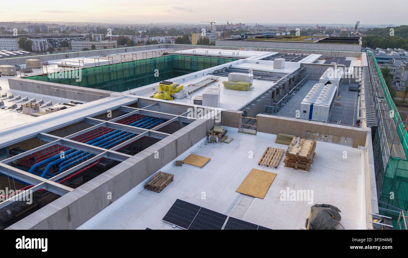 Vista aerea del tetto di un data center AI con sistemi di raffreddamento HVAC, tubazioni industriali e pannelli solari in costruzione a Cracovia, Piccola Polonia Foto Stock