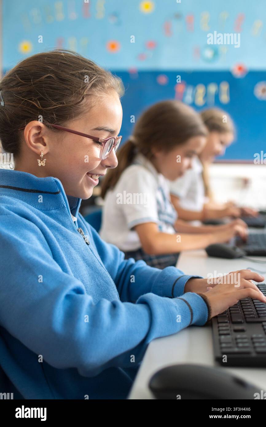 Studente delle elementari che utilizza un computer fisso durante una lezione di tecnologia informatica in un'aula moderna. Foto Stock