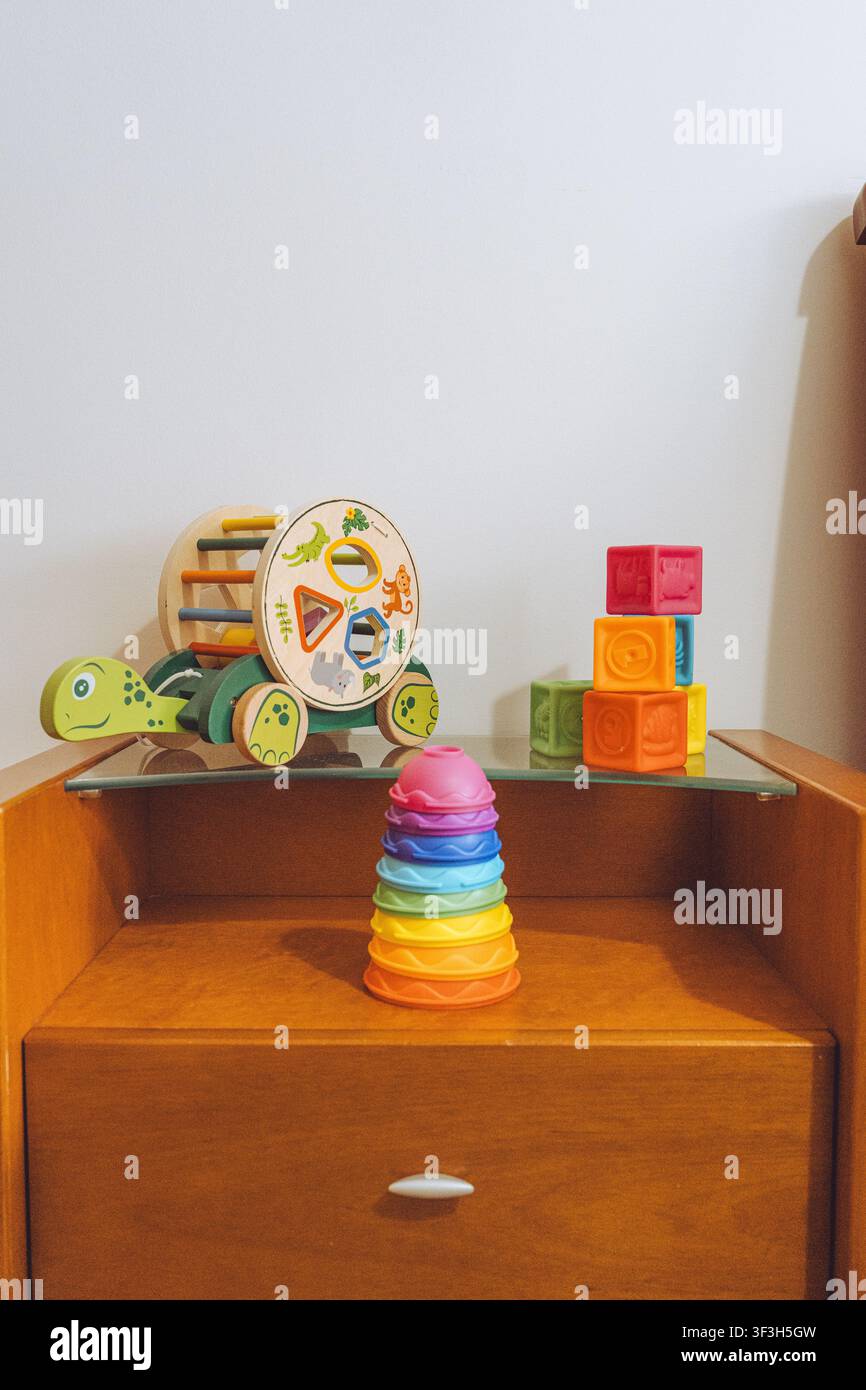 Set di giocattoli colorati per lo sviluppo del bambino su comodino in legno Foto Stock