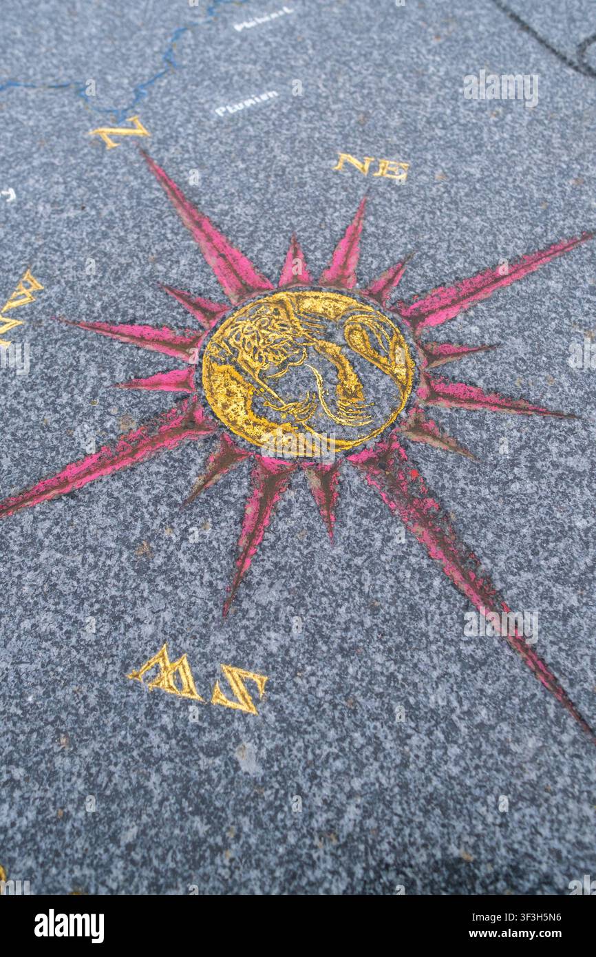 Vista ravvicinata di una rosa dei venti dipinta e di un marcatore di orientamento con le lettere N e NE su un pavimento di pietra a Plerin, Cotes-d Armor, Francia a dicembre Foto Stock
