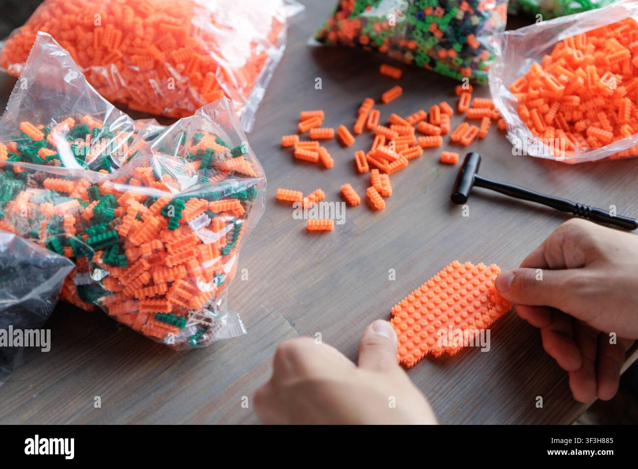 Mani che assemblano blocchi di costruzione in plastica vivaci, ideali per potenziare la motricità fine e il pensiero logico nei bambini attraverso il gioco creativo e Foto Stock