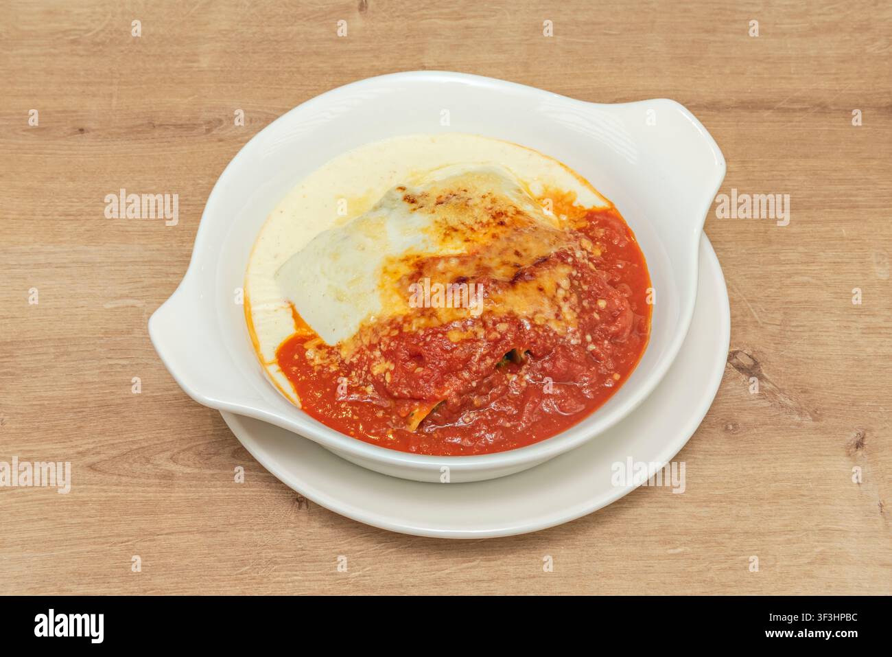 Cannelloni di pasta cotti al forno, ricoperti di formaggio fuso e ricca salsa di pomodoro, metà ricoperti di besciamella Foto Stock