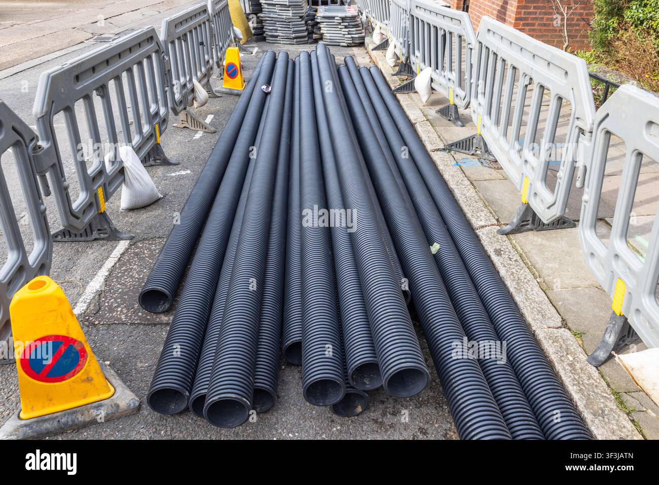 Tubi di plastica neri posati sulla strada per lavori di costruzione Foto Stock