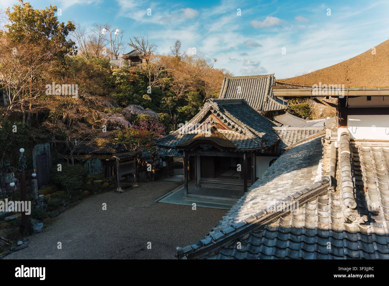 Tempio antico giapponese tradizionale con tetto a tegole grigie e giardino fiorito in una giornata soleggiata a Yoshino, Nara, Giappone Foto Stock